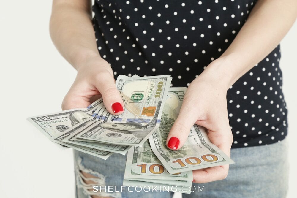 Woman holding cash in hand, from Shelf Cooking 
