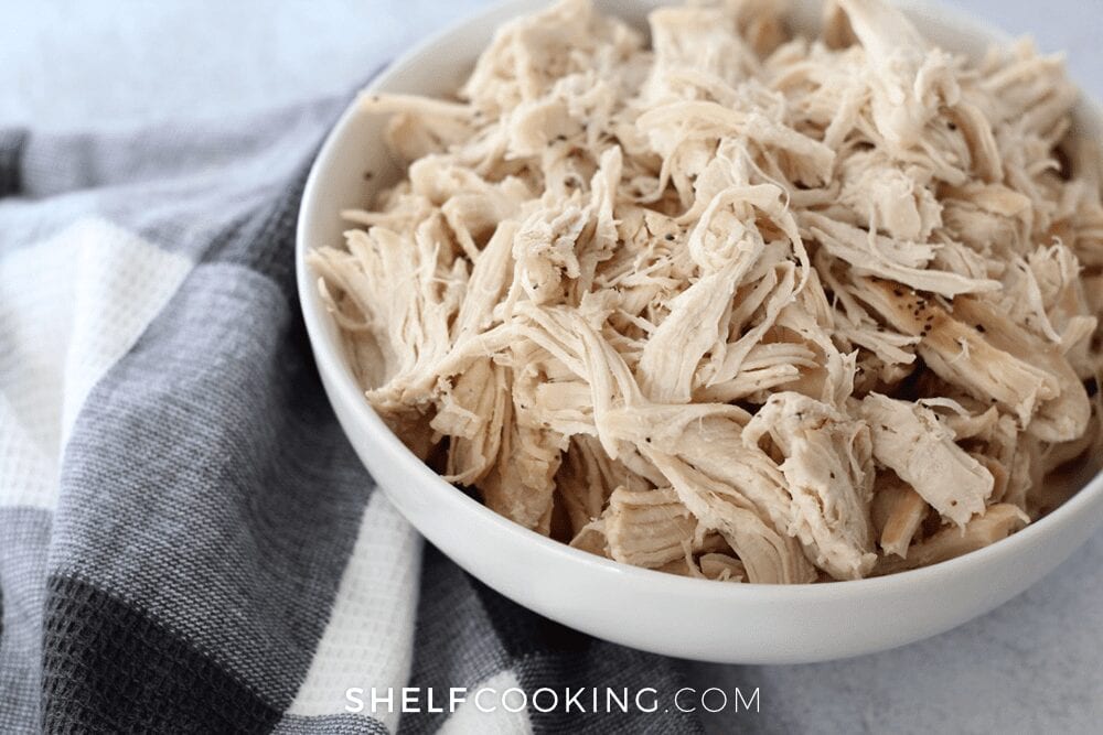 Instant Pot shredded chicken in a white bowl, from Shelf Cooking 