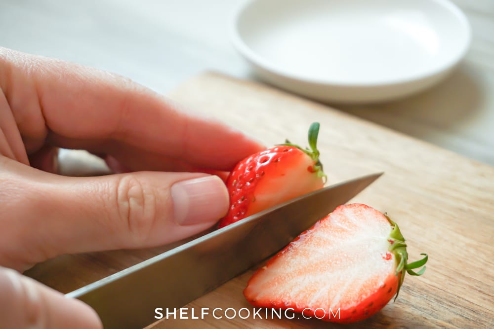 Hands cutting strawberries on a cutting board, from Shelf Cooking
