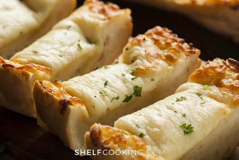 Cheesy garlic bread on a cutting board, from Shelf Cooking