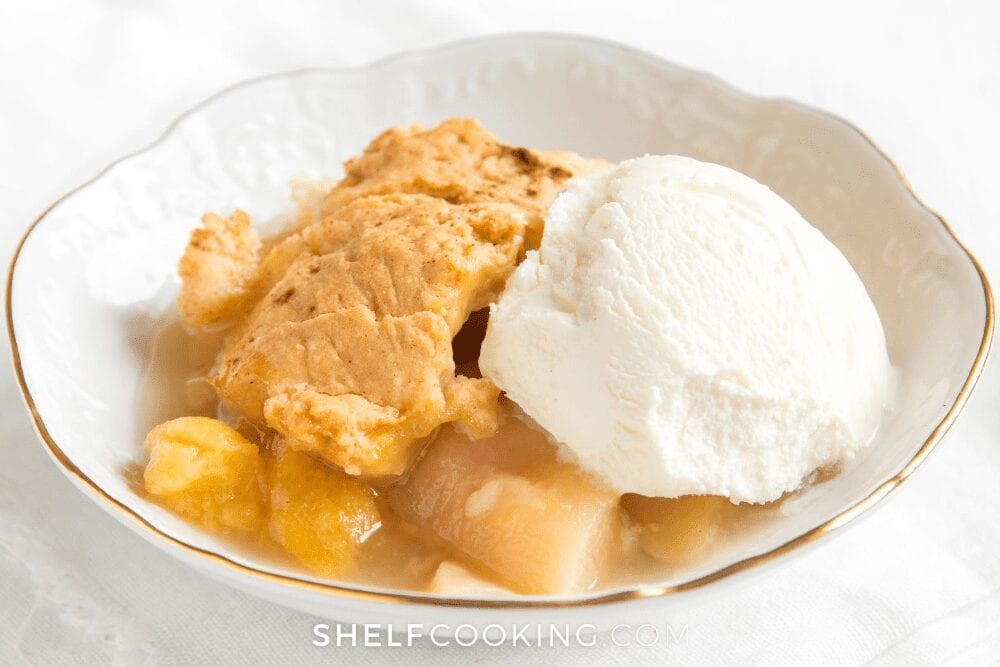 close up of a scoop of vanilla ice cream on top of peach cobbler, from Shelf Cooking