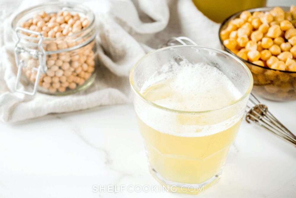 chickpeas and glass of chickpea juice on white marble counter, from Shelf Cooking