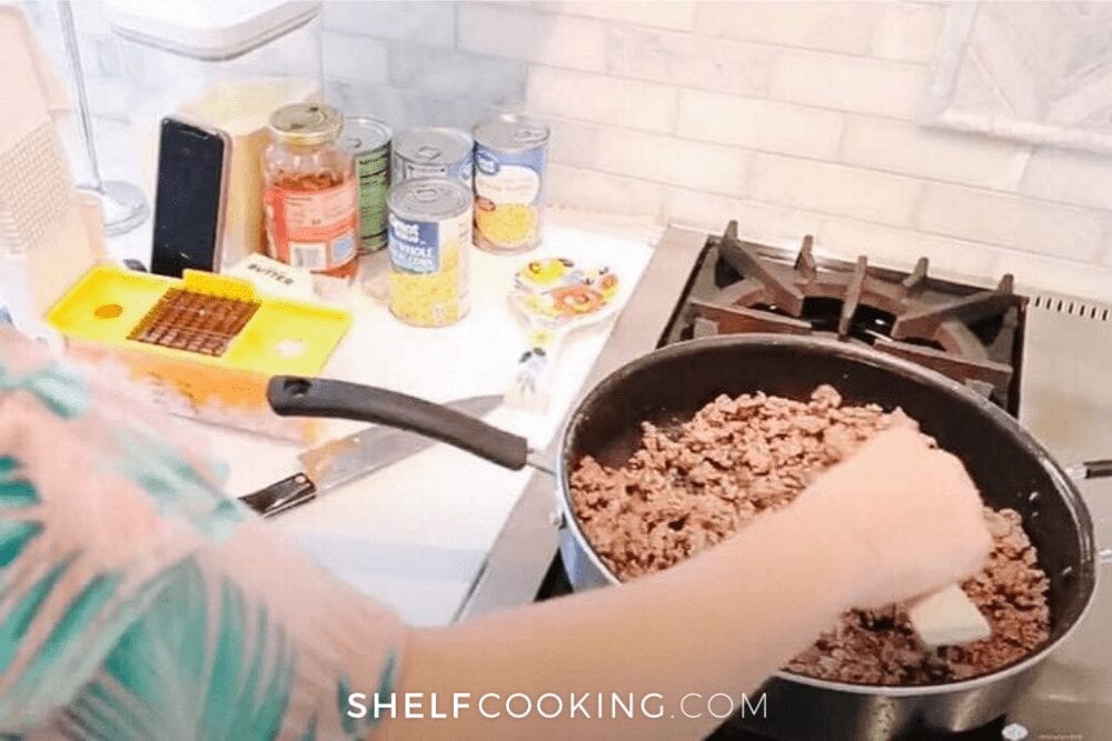 A woman cooking ground beef in a skillet on the stove, from Shelf Cooking