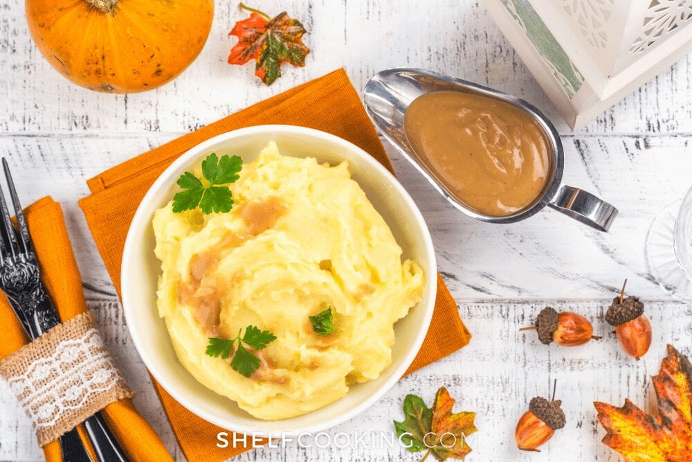 Mashed Potatoes and gravy on a counter with orange place mats from Shelf Cooking 