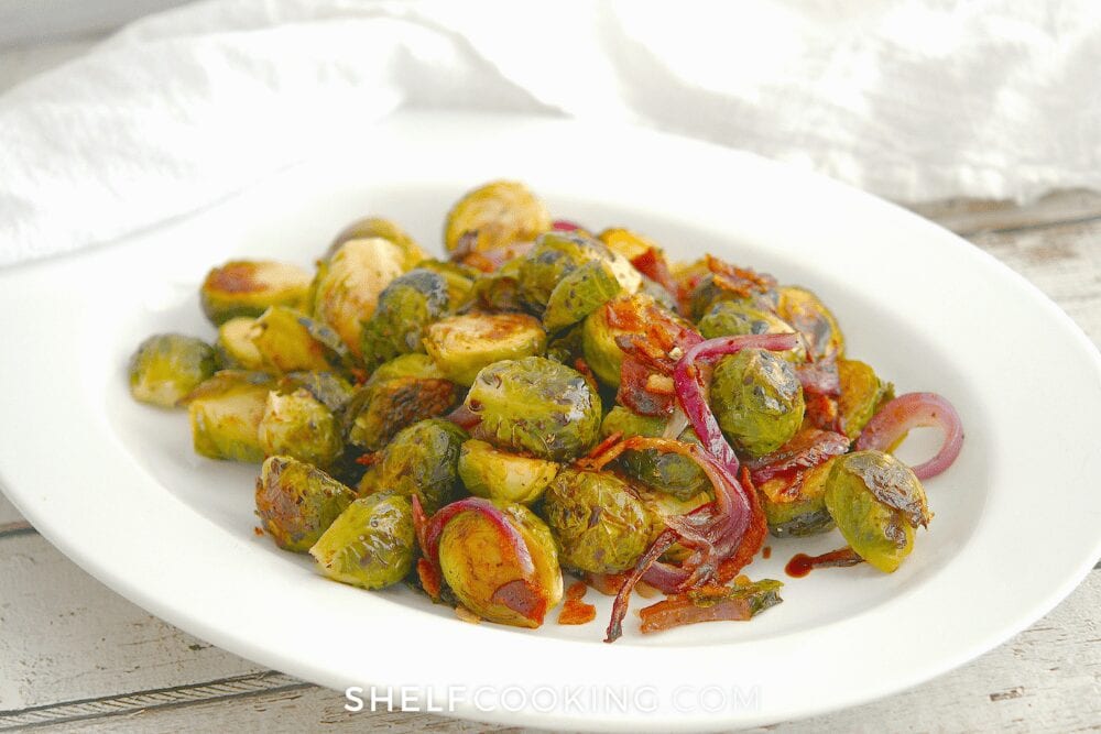 roasted Brussel sprouts on a white plate, from Shelf Cooking.