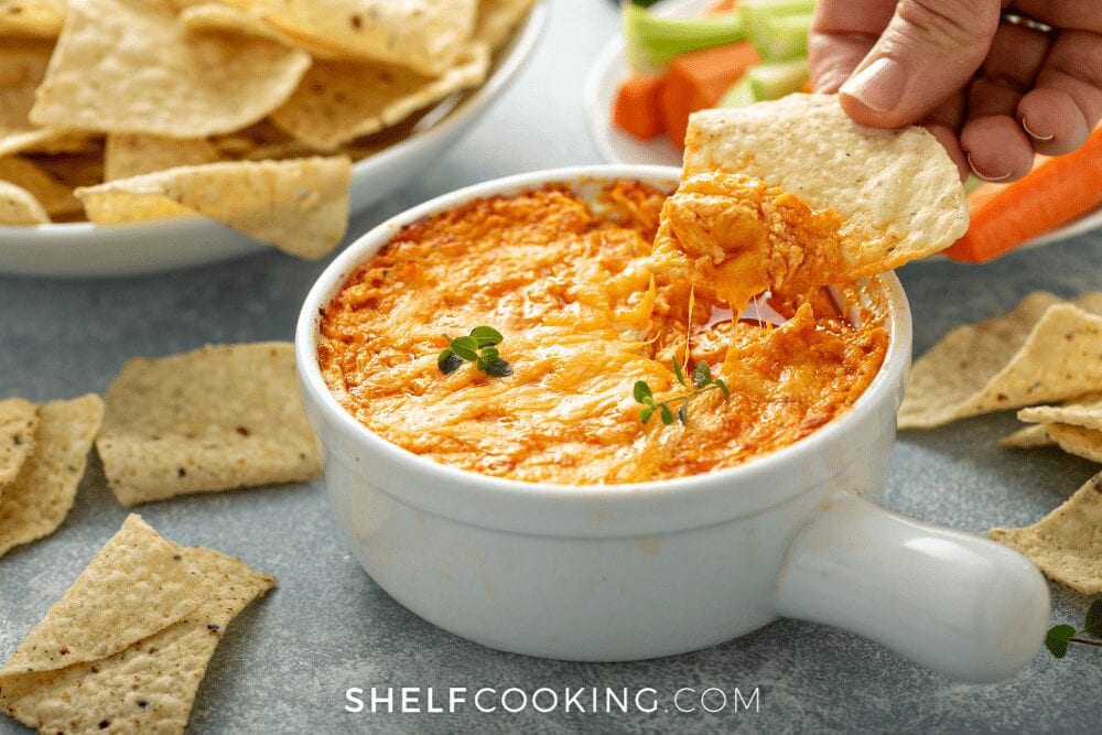 dipping a chip into buffalo chicken dip, from Shelf Cooking
