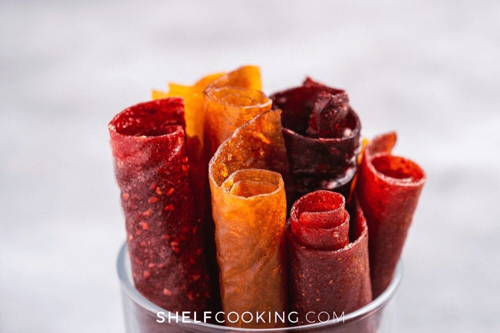 Homemade fruit leathers rolled up in a cup from Shelf Cooking. 