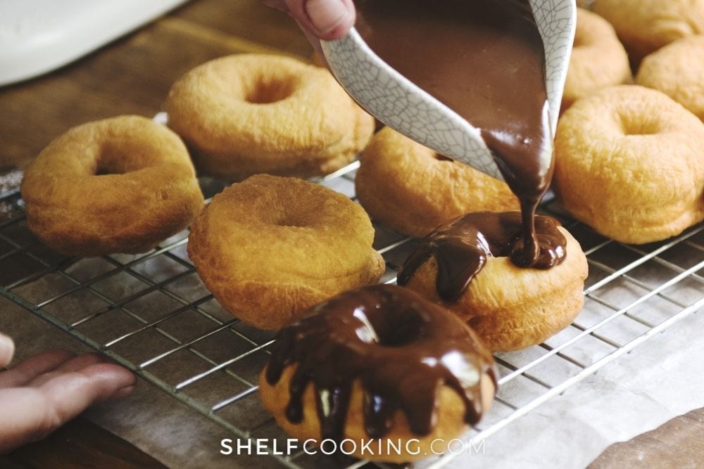 pouring chocolate on homemade donuts, from Shelf Cooking