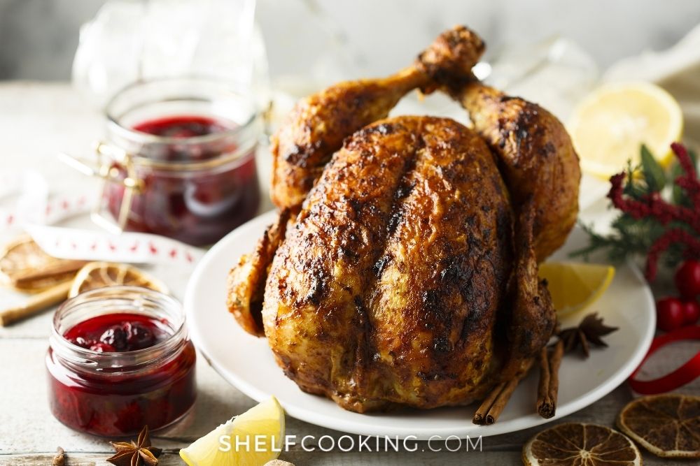 Smoked chicken on a plate with holiday decor around from Shelf Cooking.