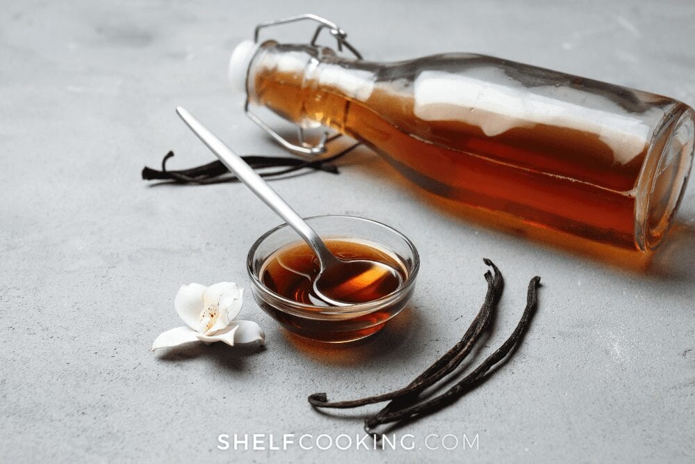 Vanilla extract in a bottle and a cup from Shelf Cooking. 