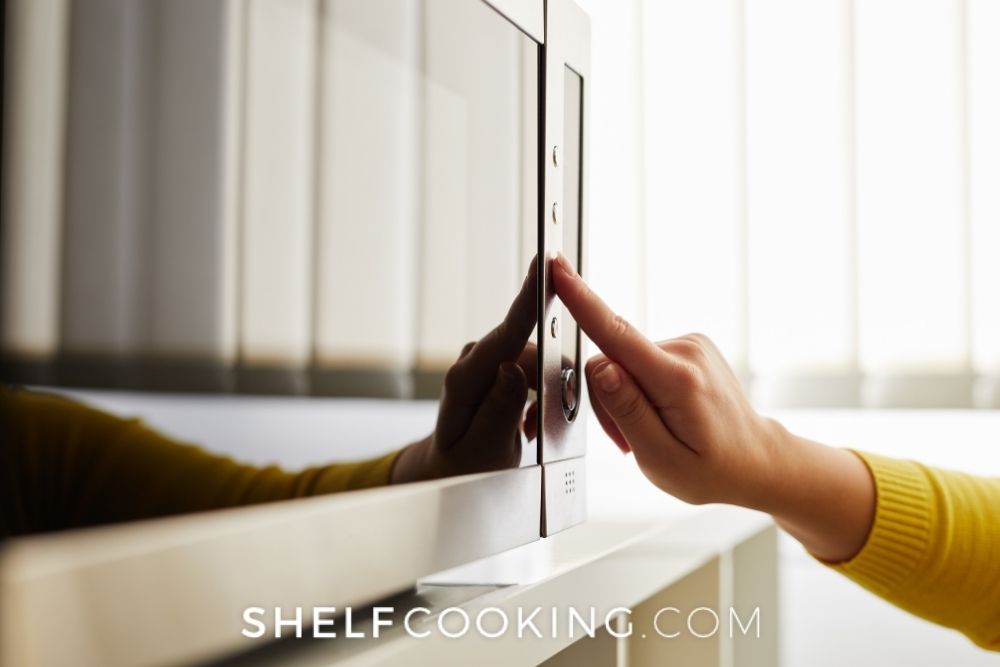 Woman turning on microwave from Shelf Cooking. 