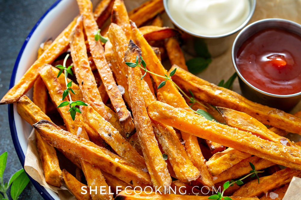 Close up image of orange sweet potato fries with ketchup and mayo dipping sauces on the side. Side dish option for French dip sandwiches. - Shelf Cooking