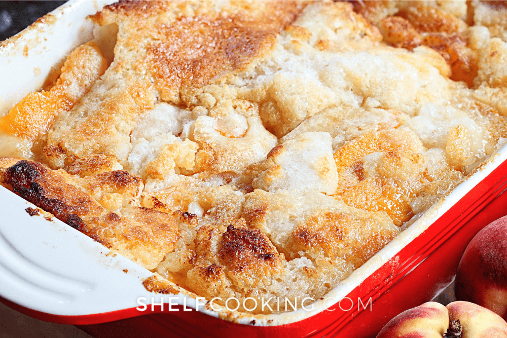 Image of a red and white baking pan filled with peach dump cake. - Shelf Cooking