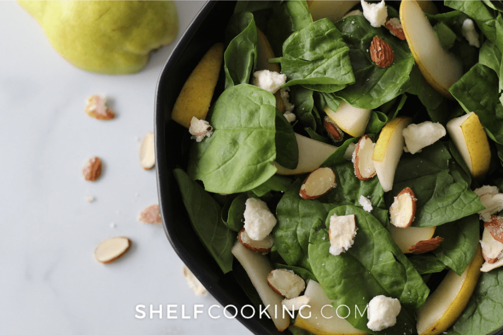 Image of a pear and spinach salad in a black bowl. - Shelf Cooking