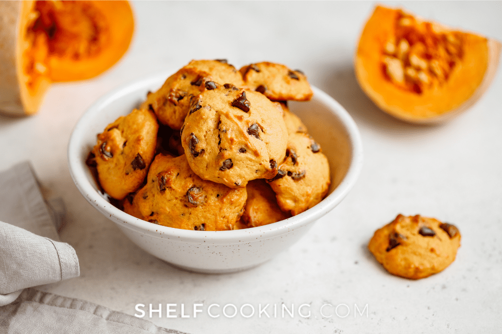 Image of a white bowl filled with pumpkin chocolate chip cookies. - Shelf Cooking