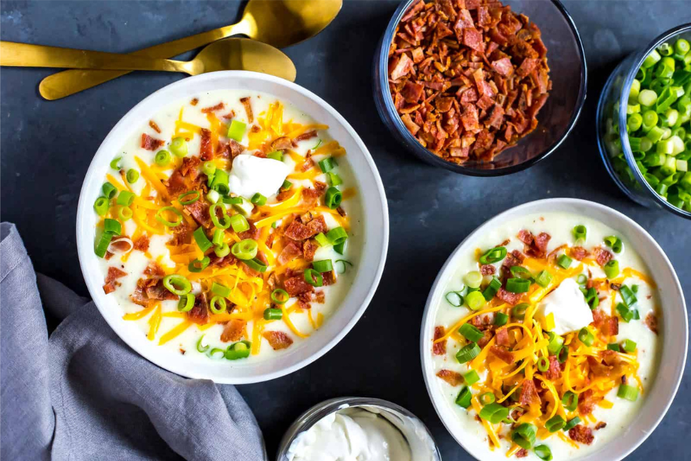 Bowls of Instant Pot loaded baked potato soup with extra bacon bits and green onions on the side. - Shelf Cooking