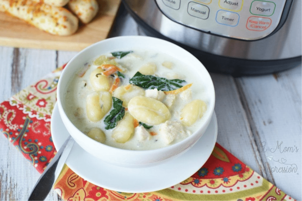 White bowl filled with chicken gnocchi soup with an Instant Pot in the background. - Shelf Cooking
