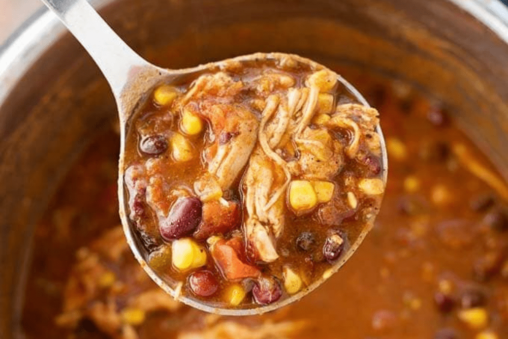 Ladle filled with Instant Pot taco chicken soup. - Shelf Cooking